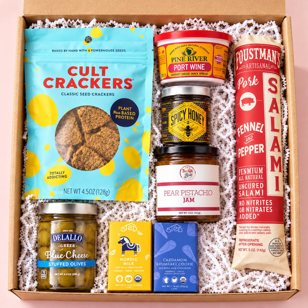 The Board Meeting shelf-stable charcuterie gift box on a light pink background