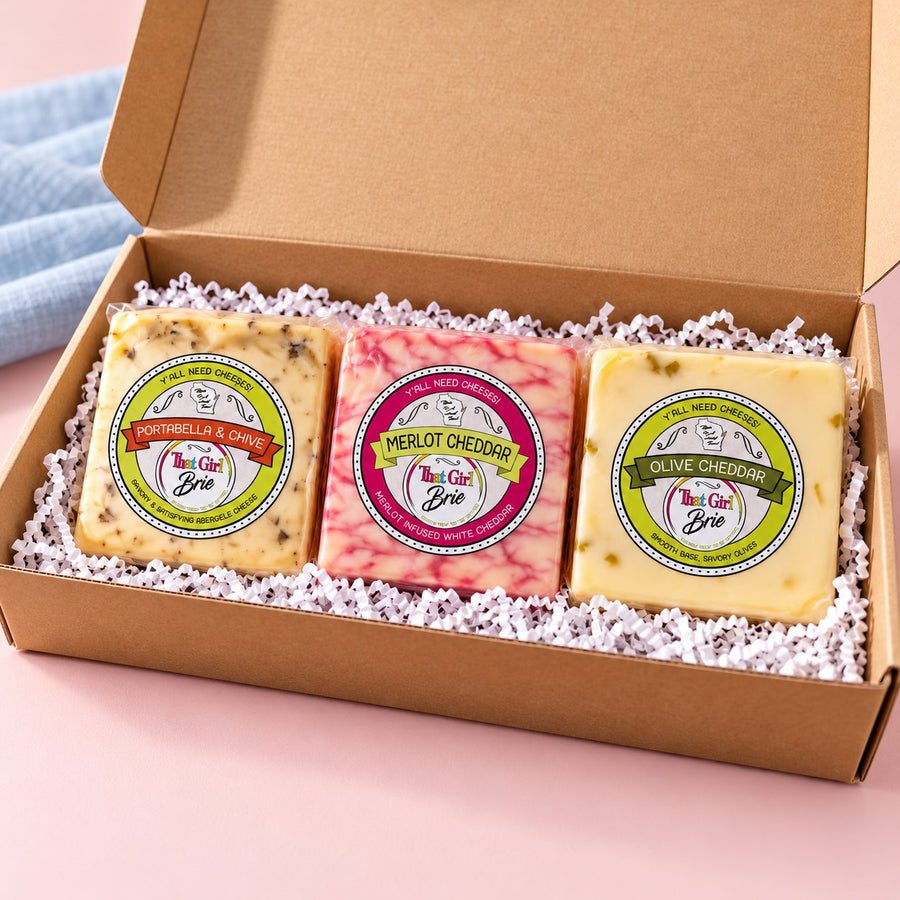 The TGB Trio cheese sampler gift box with three 8 oz bricks beside a blue linen