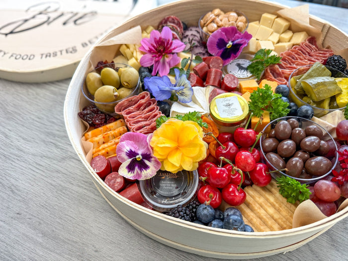 How to make a charcuterie board: a finished board with cheese, salami, fruit and edible flowers