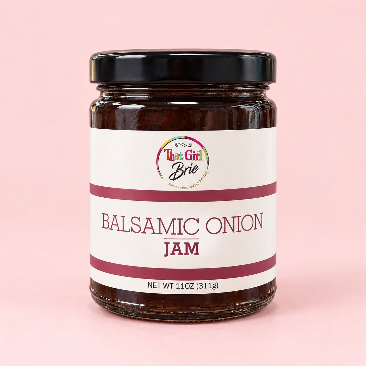 Jar of That Girl Brie Balsamic Onion jam on a light pink background