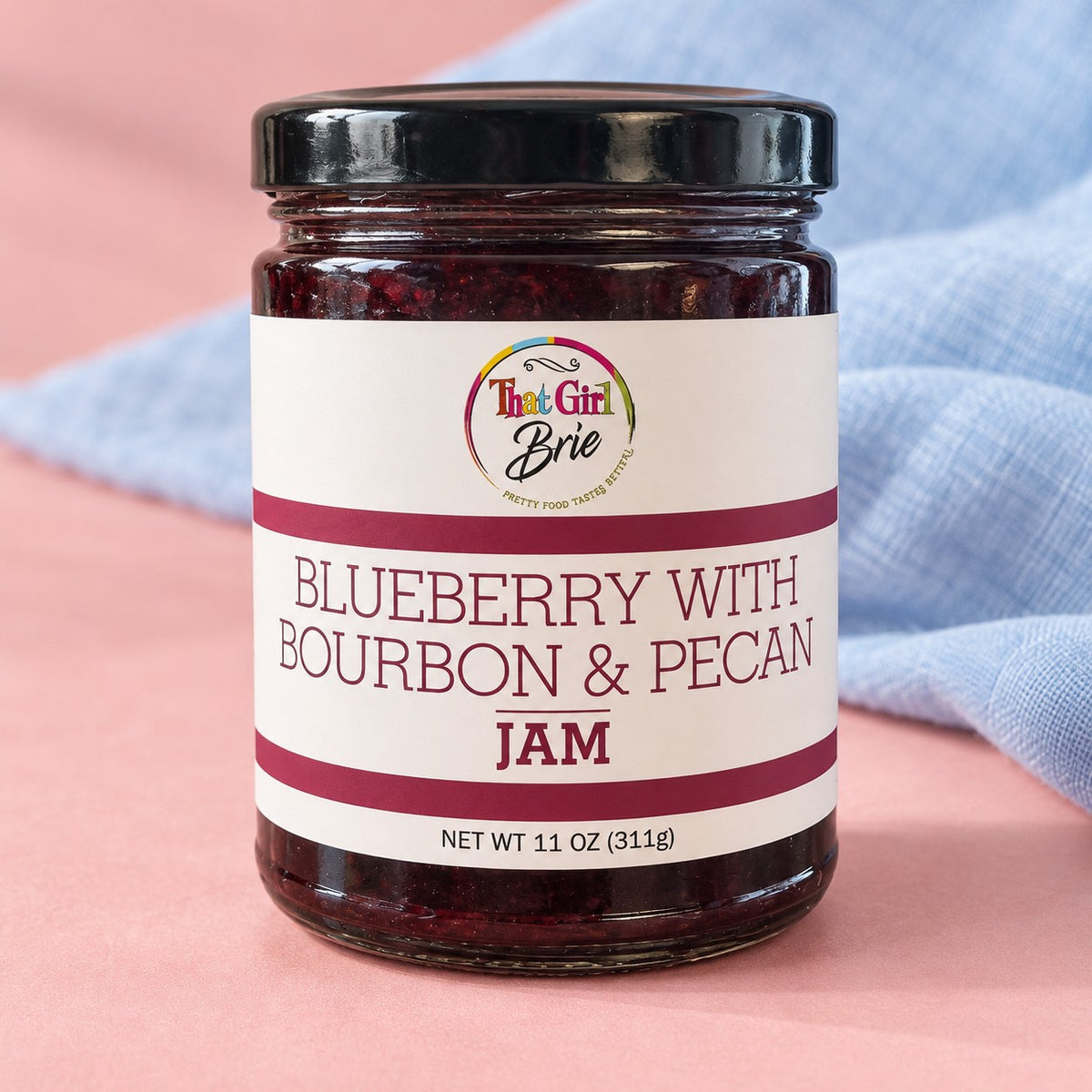 Blueberry bourbon jam with pecans in a That Girl Brie jar with a blue linen napkin