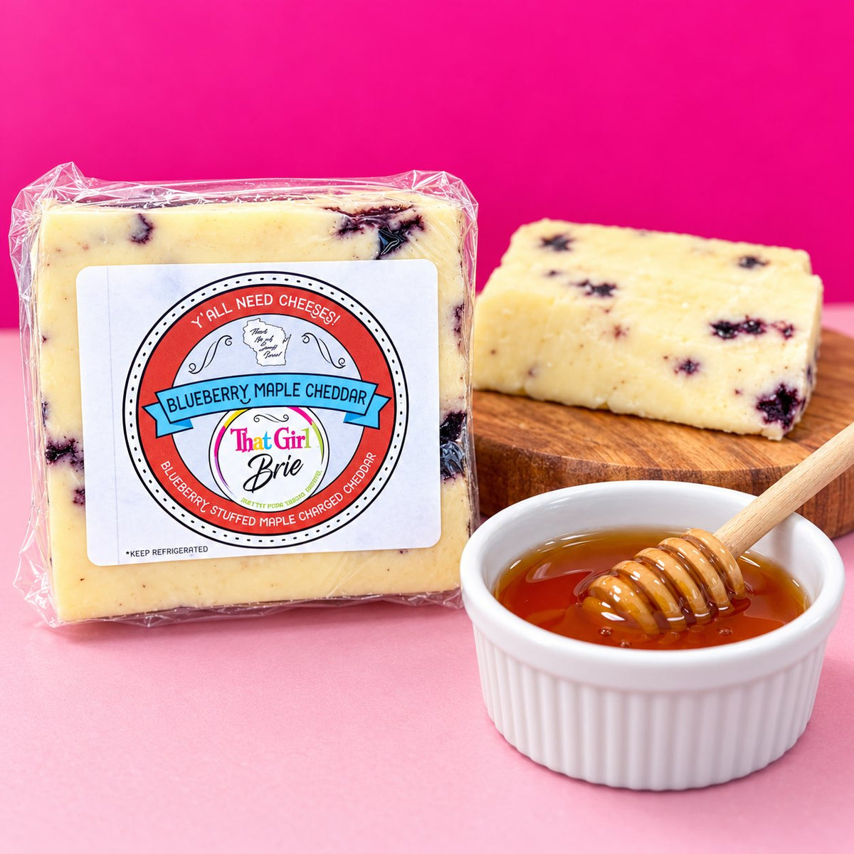 Blueberry Maple Cheddar block with a honey dipper on a hot pink background