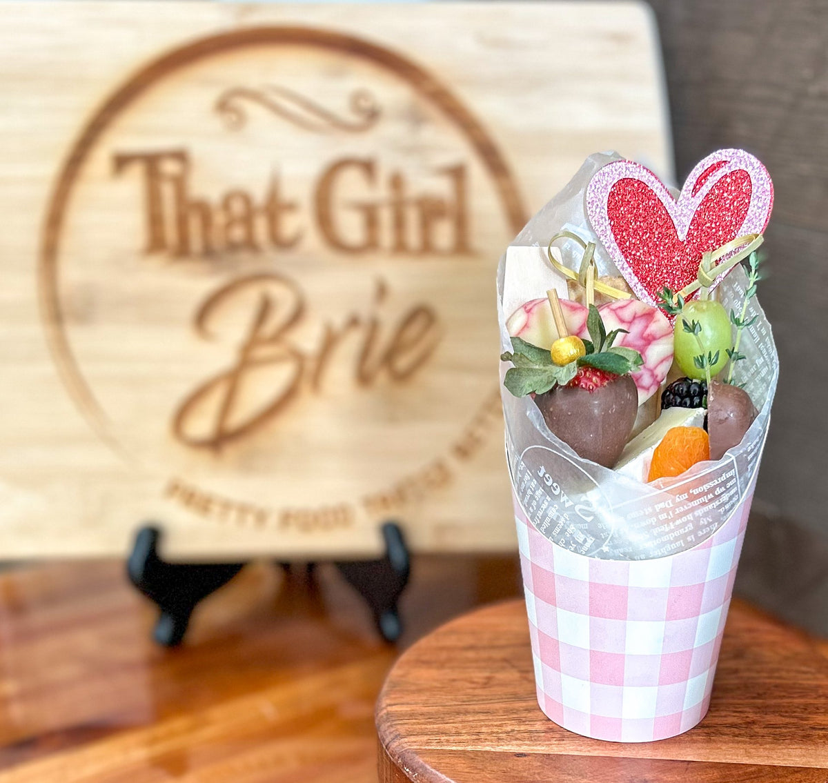 Valentine's charcuterie cup in pink gingham with chocolate covered strawberries, marbled cheese and a glitter heart