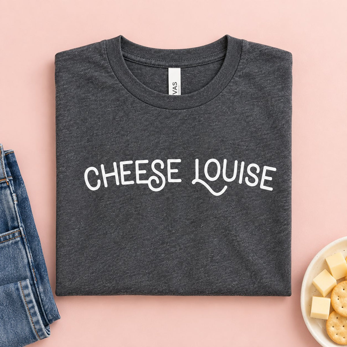 Cheese Louise t-shirt folded flat with jeans, cheese cubes and crackers