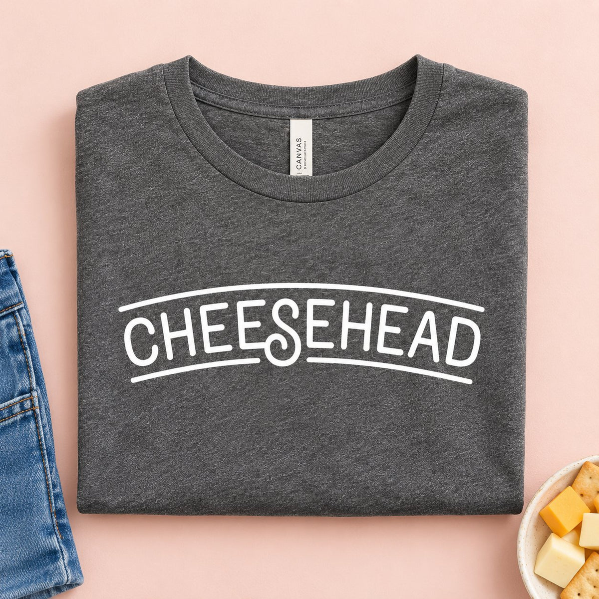 Cheesehead t-shirt folded flat with jeans, cheese cubes and crackers