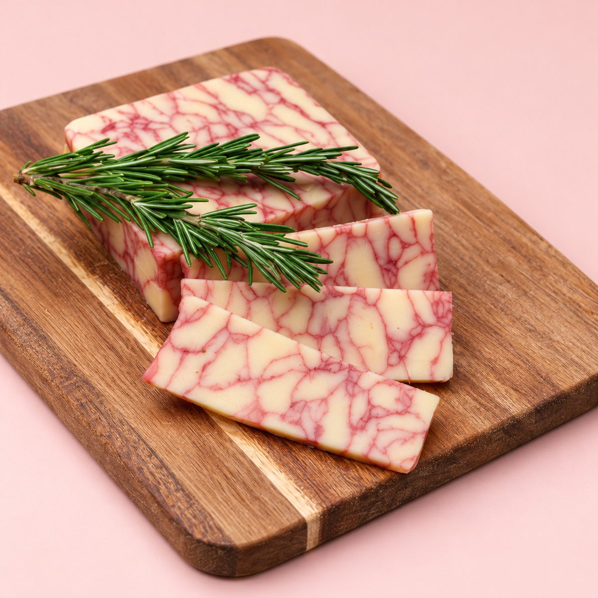 Merlot Cheddar wine cheese, marbled ruby red, sliced on a wooden board with fresh rosemary