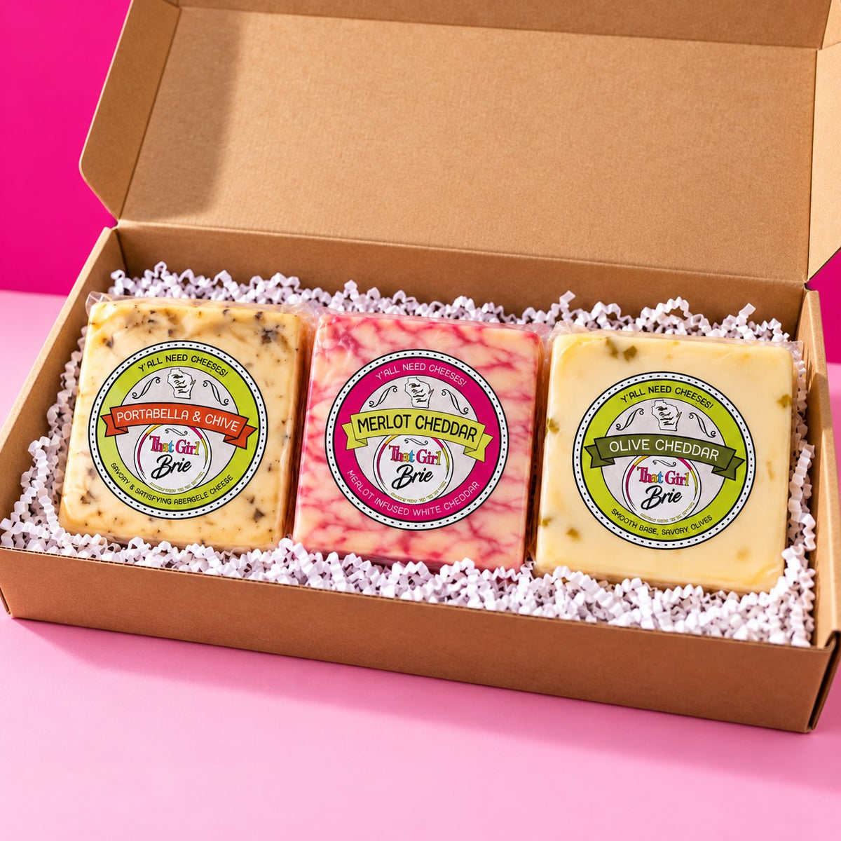 The TGB Trio cheese sampler gift box, a cheese gift set, on a hot pink background