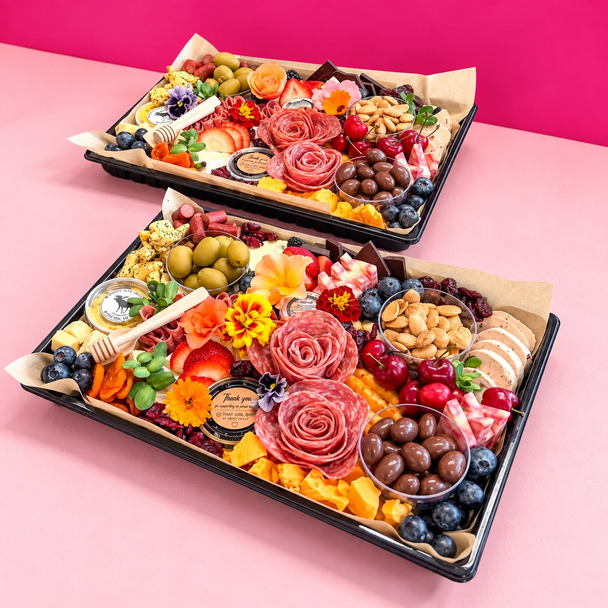 Two Gather Board charcuterie platters with cheeses, cherries and honey in front of a pink wall