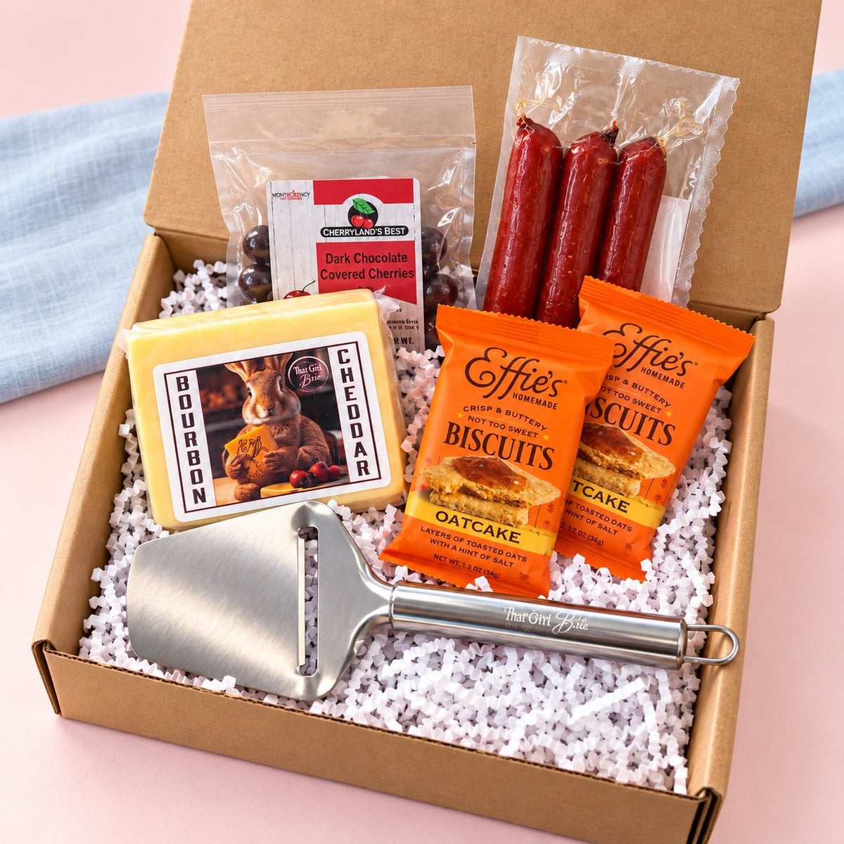 The Wisconsin Nightcap, a cheese and sausage gift box, beside a blue linen